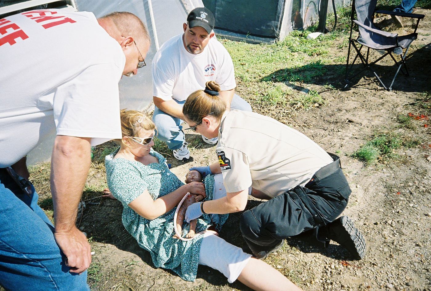 A team treating a seated patient holding an infant manikin in Dunn, 2007